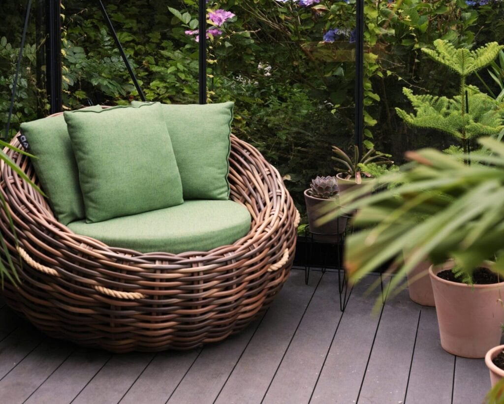 Relax in a wicker armchair amidst vibrant plants and flowers in a greenhouse sanctuary.