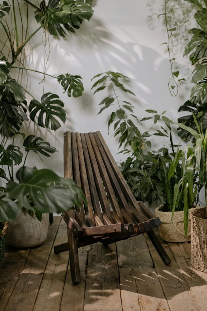 A beautifully crafted wooden chair surrounded by lush indoor plants on a wooden floor.